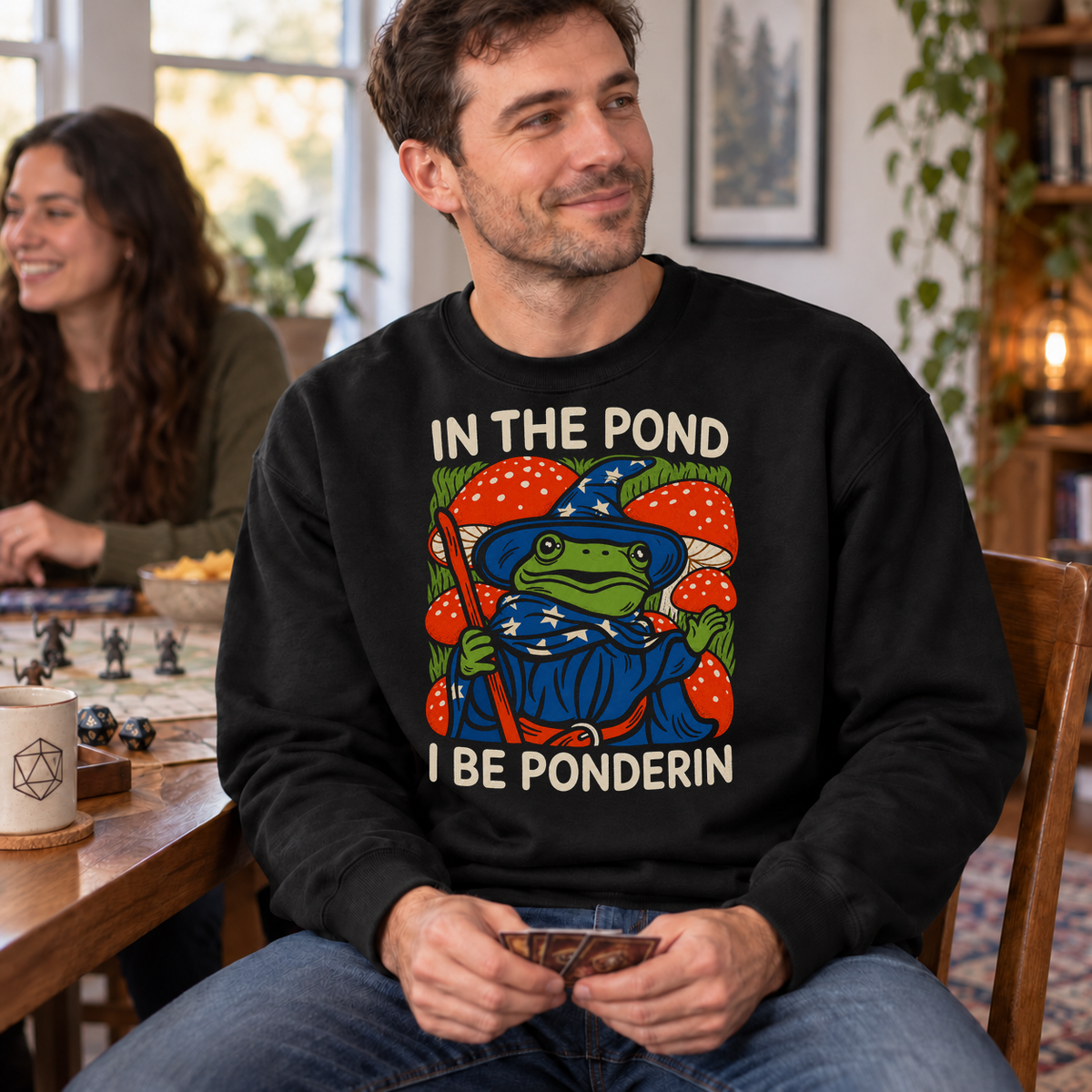 In the Pond I Be Ponderin’ black DnD sweatshirt worn by a man at game night